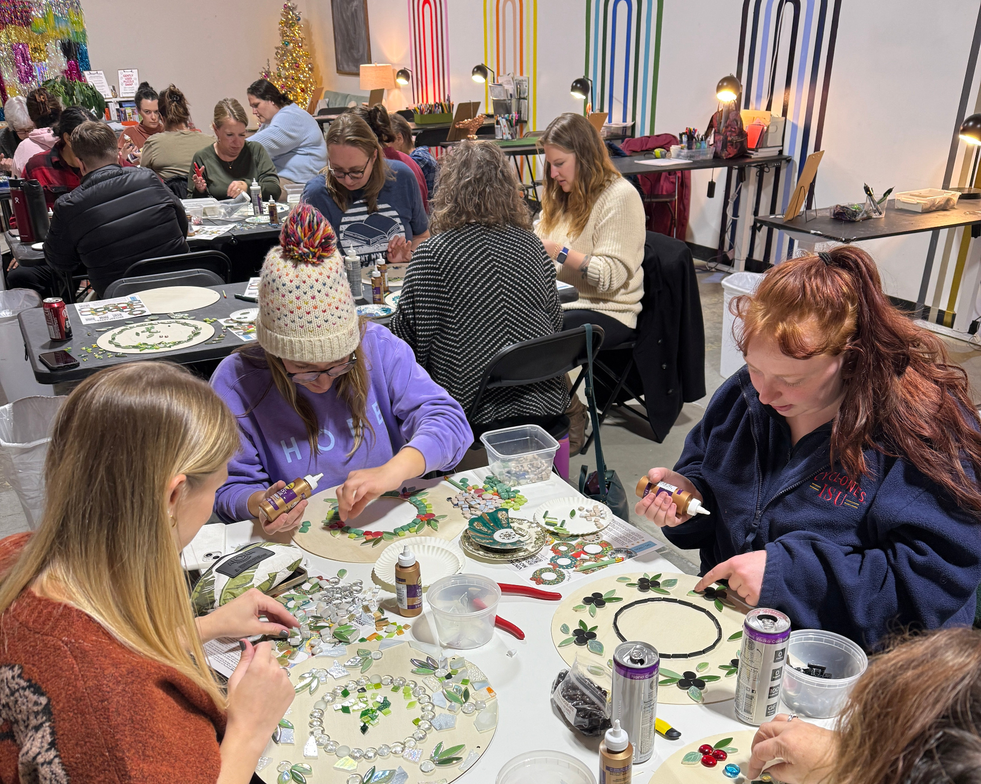 Group of people making mosaic wreaths at a diy art studio.